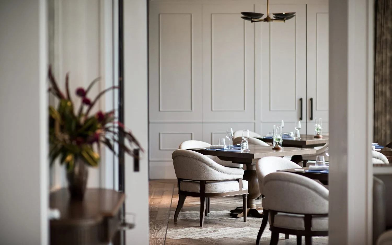 Côte by Mauro Colagreco - add panelled dining corner dramatic floral arrangement cane chairs