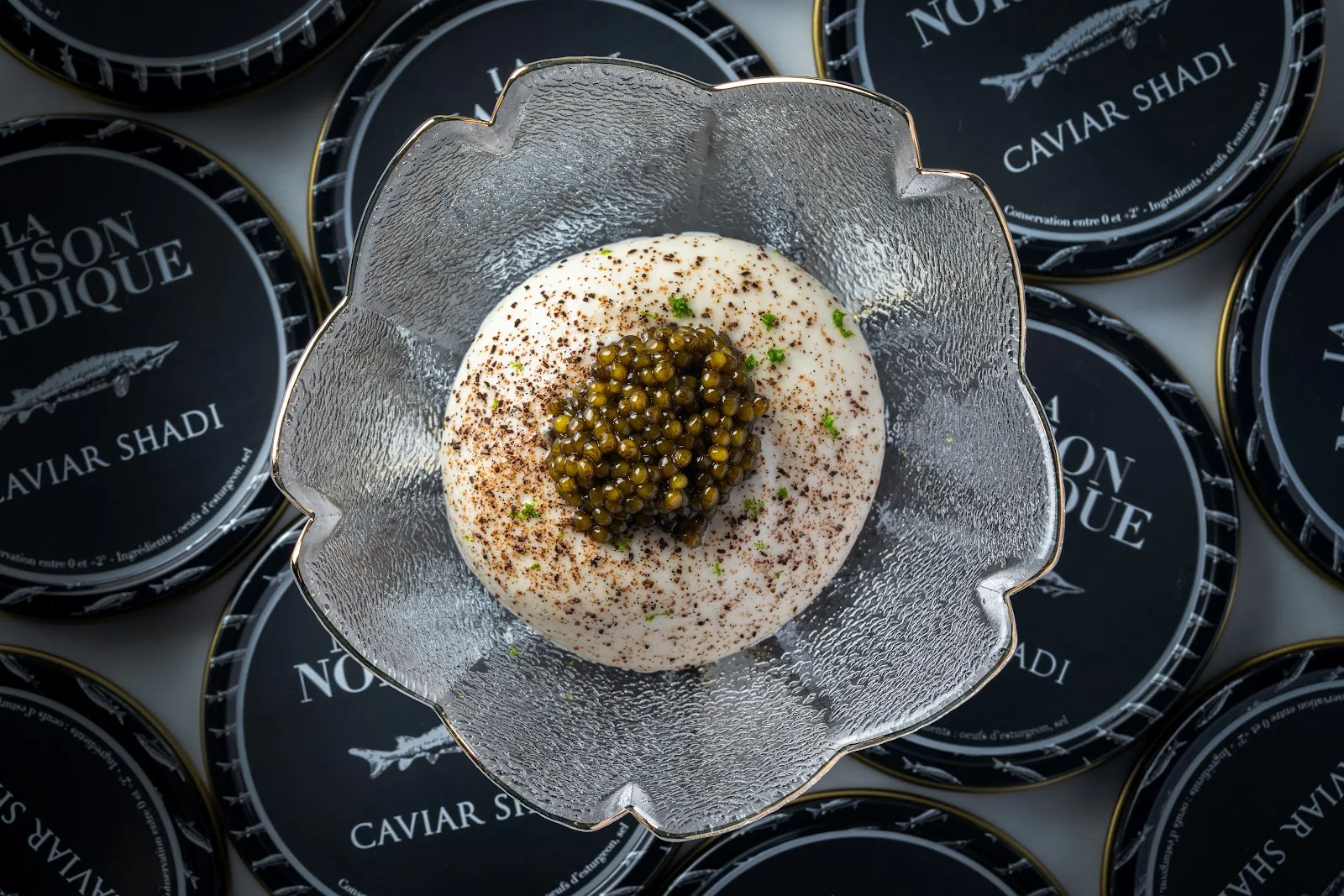 Duet by David Toutain - fix signature caviar course caviar over pannacotta dome in a petal shaped glass bowl set on caviar shadi tins plated dish