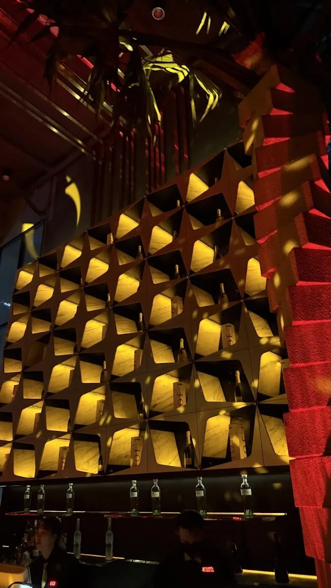 Levels Club & Lounge - fix signature gold quilted cushioned cube feature wall lit warm gold red staircase at right bottle ledge clean architecture