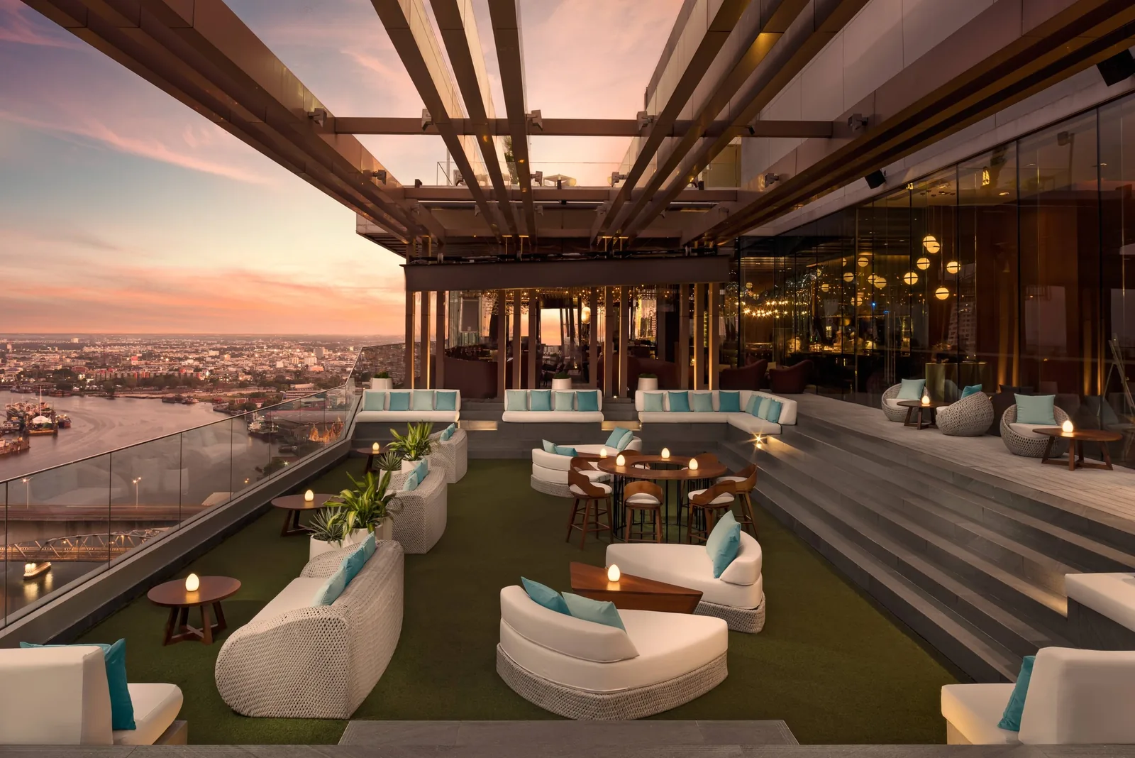 SEEN Restaurant - fix seen rooftop terrace lounge at sunset white curved sofas green lawn seating area pergola dramatic sky over the chao phraya