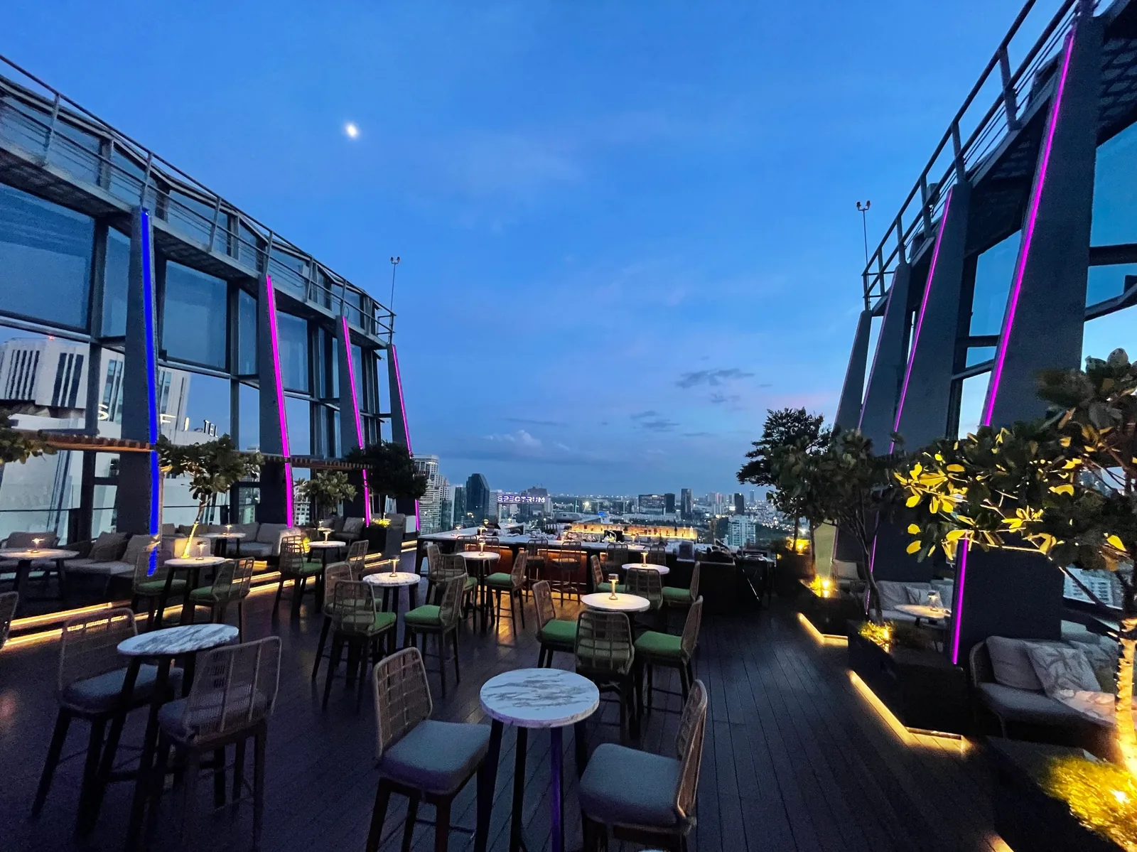 Spectrum Lounge - fix spectrum open air rooftop terrace at blue hour dining tables purple lit columns greenery sukhumvit skyline