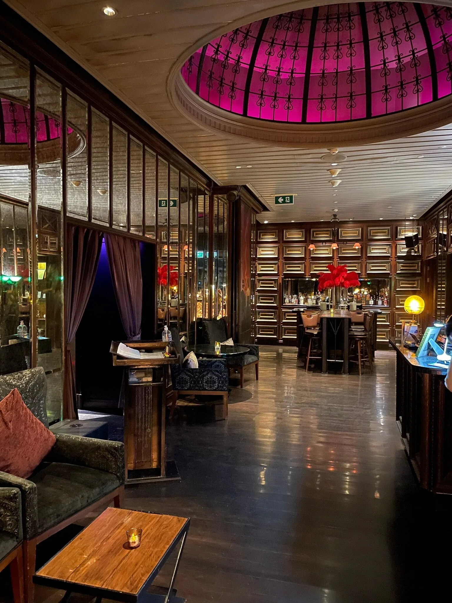 The Speakeasy Rooftop Bar - fix the speakeasy elegant 1920s inspired indoor lounge wood paneling leather seating warm lamplight and the signature pink lit dome beyond
