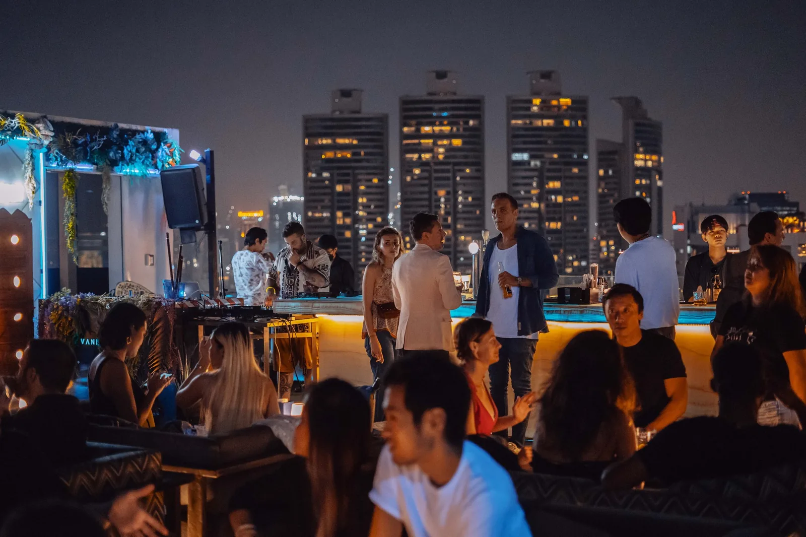 Vanilla Sky / Madura - fix vanilla sky open air rooftop bar at dusk signature green lit bar counter guests dj area and bangkok skyline
